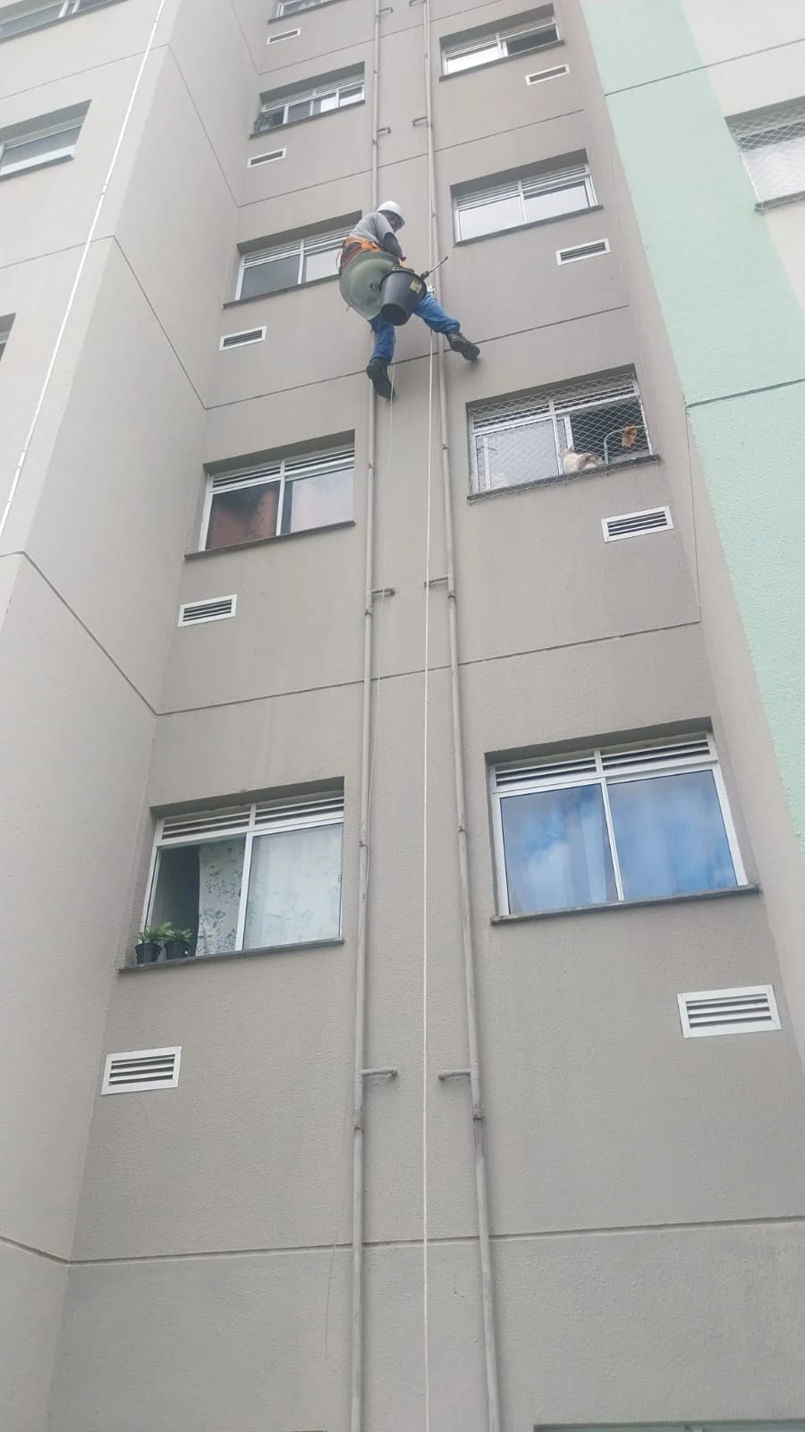 Profissional executando trabalho em altura por acesso com cordas em fachada de edifício